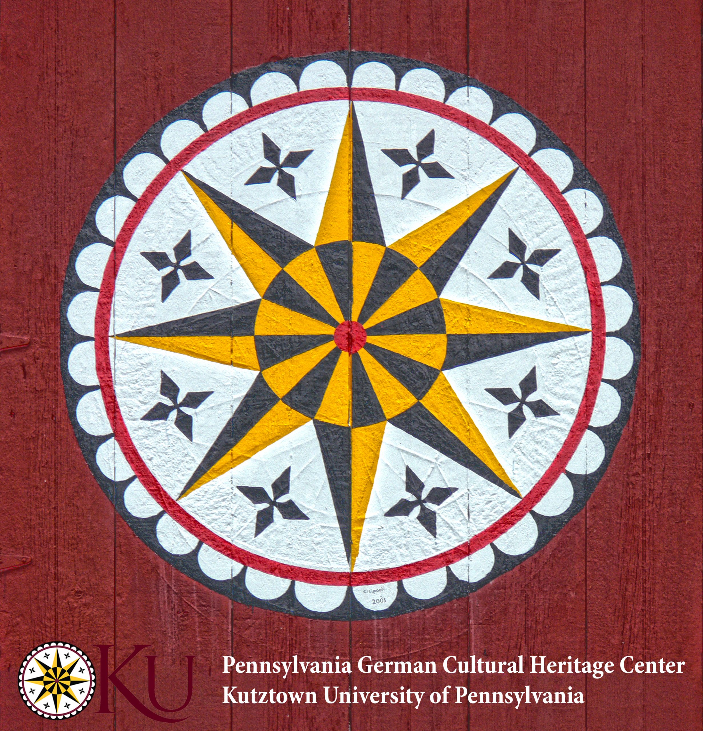 An 8-pointed yellow and black star is surrounded by 8 4-pointed stars on a white background. These symbols are surrounded by a red line and a black and white scalloped bordered circle. This barn star is painted on red barn siding.